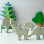 2 Ostheimer wooden elephant toy figures stood on a white table in front of some wooden Bumbu tree toys