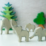 2 Ostheimer wooden elephant toy figures stood on a white table in front of some wooden Bumbu tree toys