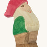 A wooden Ostheimer Eugen dwarf figure wearing a green top, brown trousers and a red hat on a cream background.