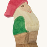 A wooden Ostheimer Eugen dwarf figure wearing a green top, brown trousers and a red hat on a cream background.