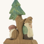 A wooden fir Ostheimer tree with the sitting and standing Ostheimer fir tree dwarves on the stand on a cream background.