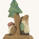 A wooden fir Ostheimer tree with the sitting and standing Ostheimer fir tree dwarves on the stand on a cream background.