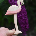 An Ostheimer wooden flamingo figure held in an adult's hand to show scale.