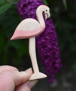 An Ostheimer wooden flamingo figure held in an adult's hand to show scale.