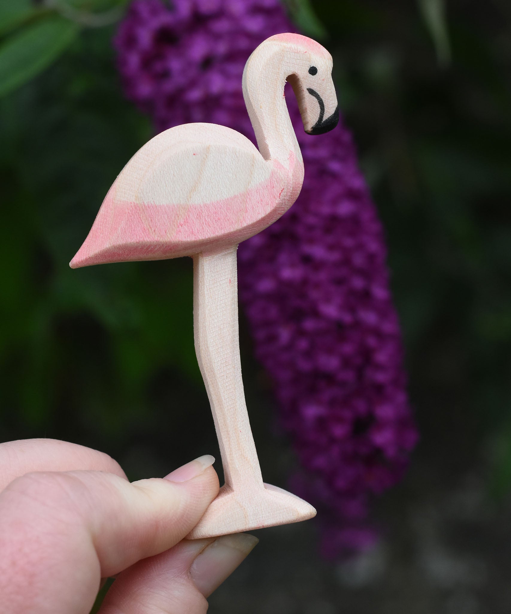 An Ostheimer wooden flamingo figure held in an adult's hand to show scale.