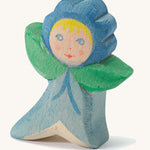 A wooden Ostheimer forget me not figure wearing a blue outfit and a matching blue hat on a cream background.