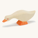 A white wooden Ostheimer goose figure with its head low on a cream background.