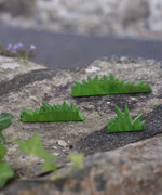 The Ostheimer Wooden green Figures set placed on a stone wall outdoors.