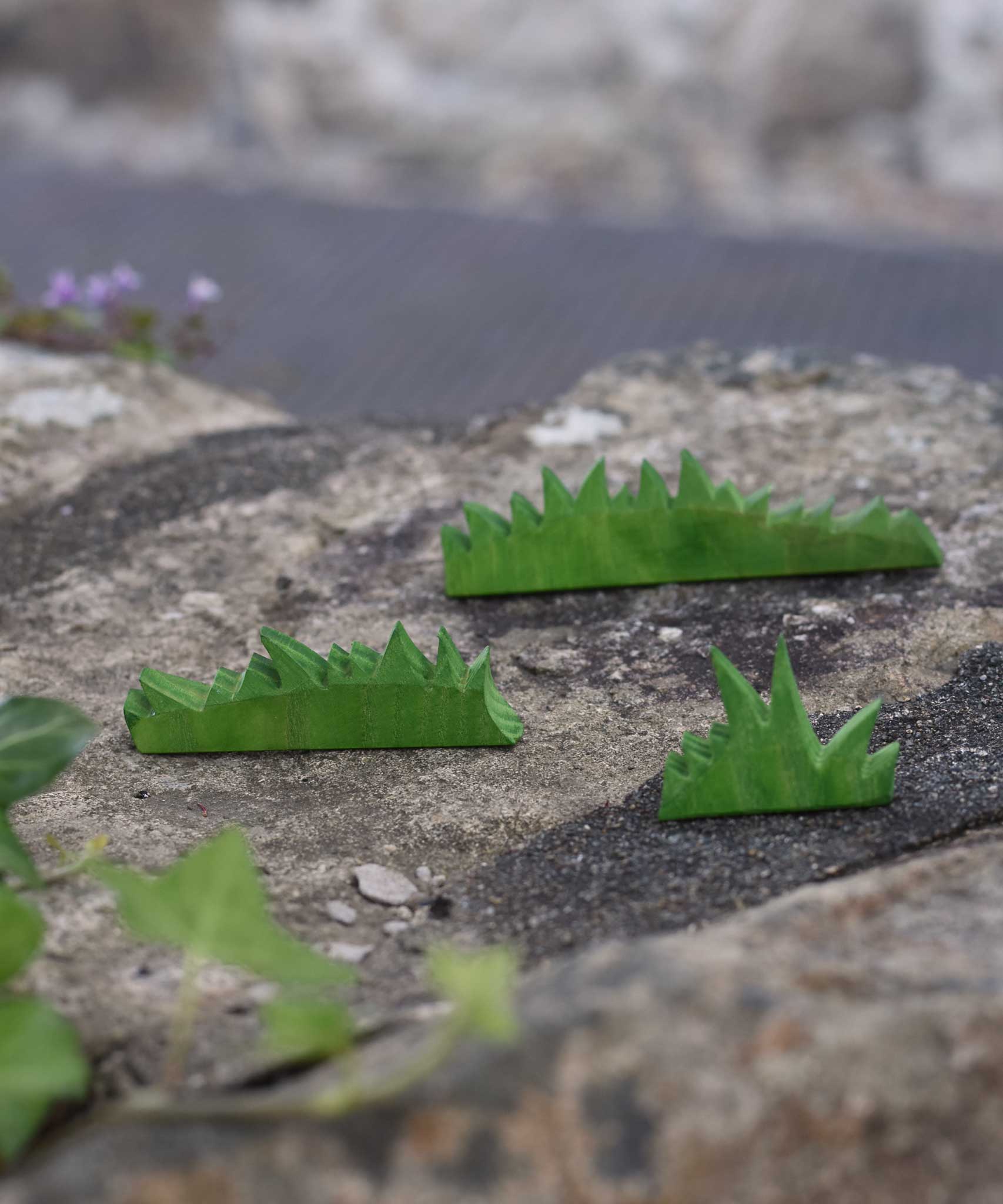 The Ostheimer Wooden green Figures set placed on a stone wall outdoors.