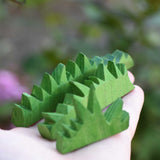The Ostheimer Wooden green grass Figures in an adults hand. The grass comes in a set of three and are perfect for small world play scenes. 