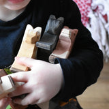 Close up of child holding three Ostheimer wooden horses in his arm. 