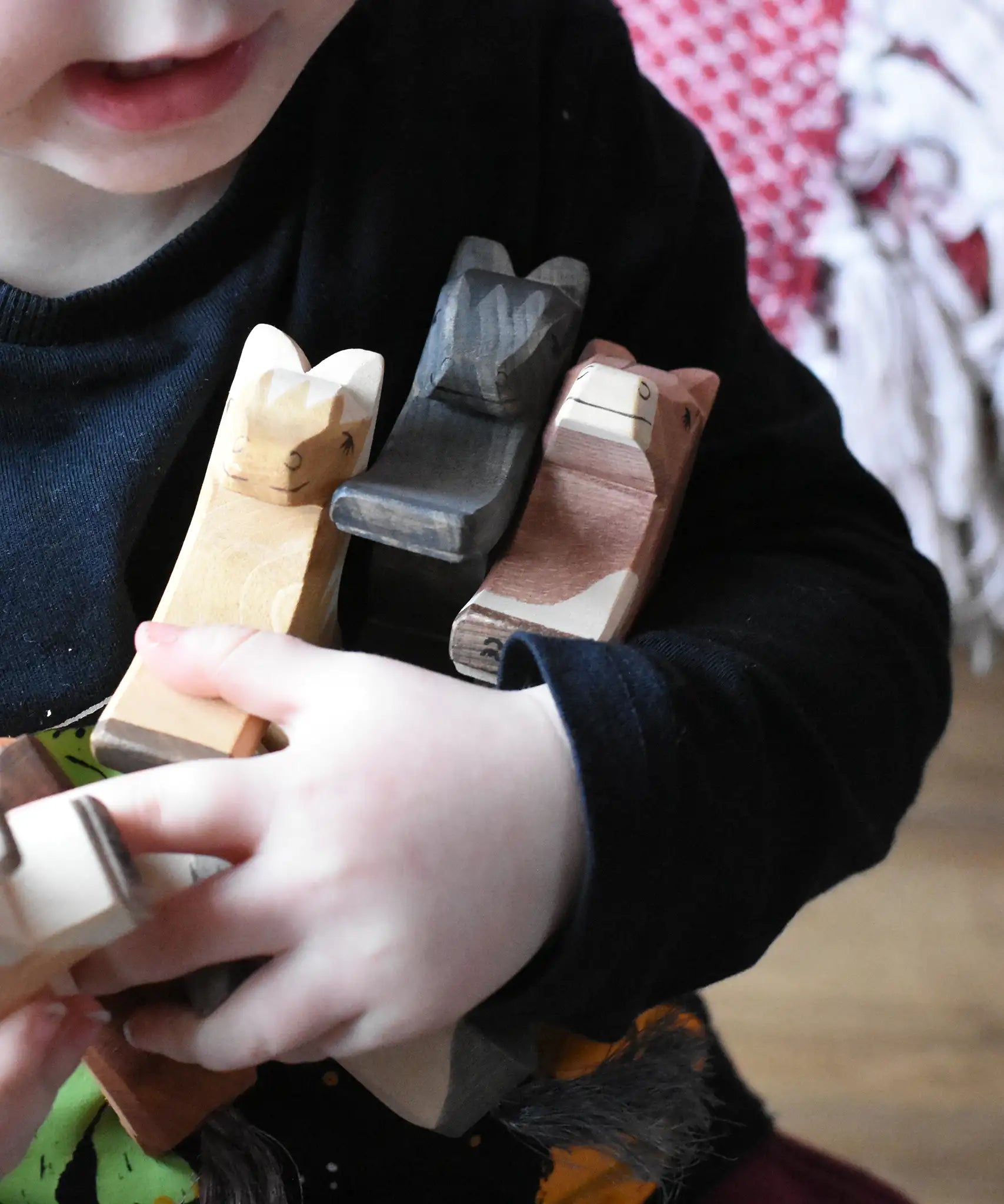 Close up of child holding three Ostheimer wooden horses in his arm. 