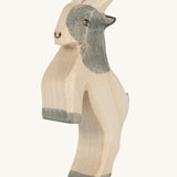 A grey and white wooden Ostheimer jumping goat figure on a cream background.