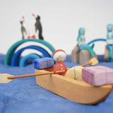  An Ostheimer lifeboat placed on blue material. There is a Santa peg doll in the boat along with wooden gifts. 