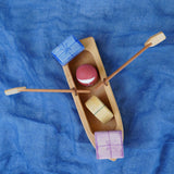 An overhead view of the Ostheimer lifeboat placed on a piece of blue material. There is a red peg doll and gifts in the lifeboat.
