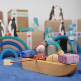  An Ostheimer lifeboat placed on blue material. There is a Santa peg doll in the boat along with wooden gifts. 