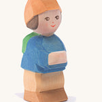 A wooden Ostheimer mo figure wearing a blue coat, orange hat and brown trousers on a cream background.