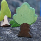 Ostheimer Wooden Oak Tree Figure placed on a stone wall outdoors. Other Ostheimer wooden figures can be seen in the background.