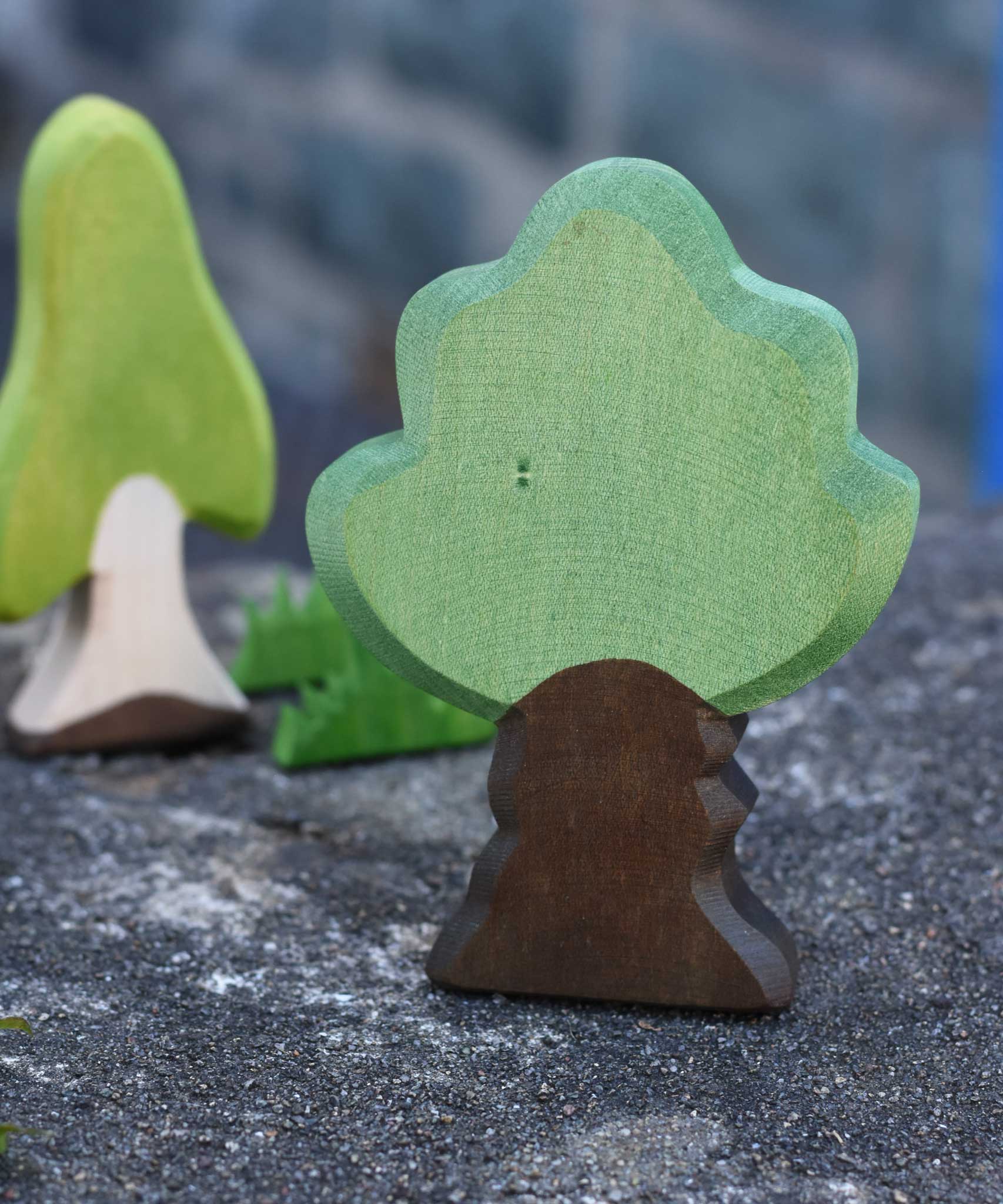 Ostheimer Wooden Oak Tree Figure placed on a stone wall outdoors. Other Ostheimer wooden figures can be seen in the background.
