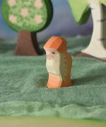 An Ostheimer orange dwarf wooden toy figure placed in a small world play scene. The dwarf figure has an orange coloured outfit with matching hat and a long white beard. The figure has been placed on a green coloured Ostheimer play scarf. This wooden figure is part of a large range of expertly hand crafted, Waldorf inspired, wooden toys here at Babipur. 