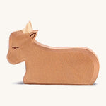 A brown wooden Ostheimer ox figure resting on a cream background.