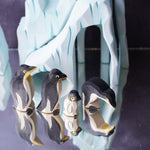 Ostheimer penguin figures placed on a reflective surface with the Bumbu icy cliffs seen in the background