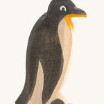 A straight standing wooden Ostheimer penguin figure on a cream background.