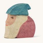 A wooden Ostheimer Peter dwarf figure wearing a purple top and a blue hat on a cream background.