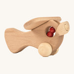 A wooden Ostheimer plane with a red peg doll sitting inside on a cream background.