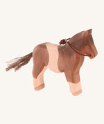 A white and brown wooden Ostheimer pony figure on a cream background.