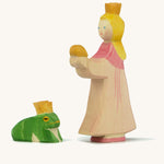 A wooden Ostheimer princess figure wearing a pink dress standing next to a king frog figure on a cream background.