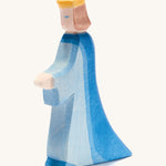 A wooden Ostheimer queen figure wearing a blue flowing dress and yellow crown on a cream background.