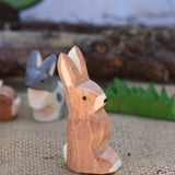 An Ostheimer wooden rabbit figure with it's ears up placed in a small world play scene. We have a full range of expertly crafted wooden toy figures and scenery available here at Babipur.