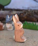 An Ostheimer wooden rabbit figure with it's ears up placed in a small world play scene. We have a full range of expertly crafted wooden toy figures and scenery available here at Babipur.