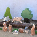 A small world play scene featuring various Ostheimer rabbit figures, green grass figures and Ostheimer trees in the background.  Check out our full range of expertly crafted wooden toy figures and scenery here at Babipur.