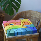 Ostheimer Rainbow Castle Blocks in a wooden tray placed on a wooden stool. 