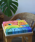 Ostheimer Rainbow Castle Blocks in a wooden tray placed on a wooden stool. 