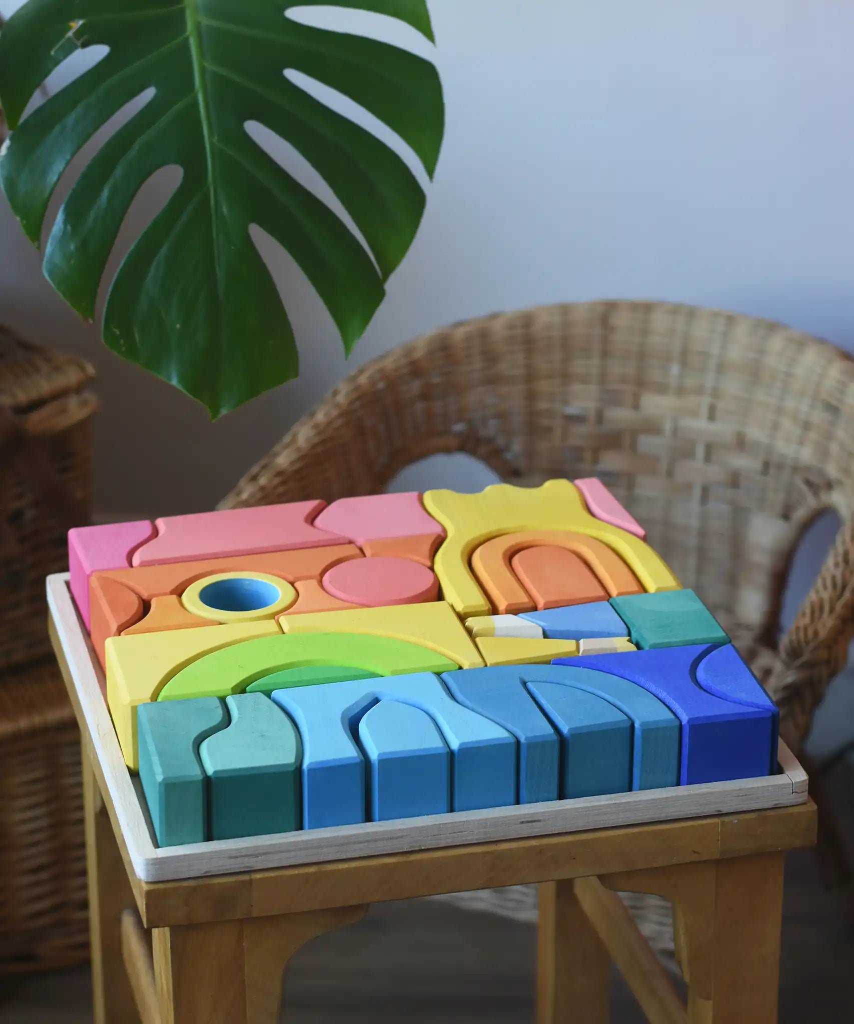 Ostheimer Rainbow Castle Blocks in a wooden tray placed on a wooden stool. 