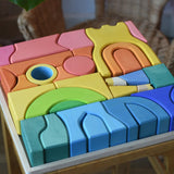 Close up of the Ostheimer Rainbow Castle Blocks in a wooden tray placed on a wooden stool. 