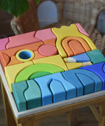 Close up of the Ostheimer Rainbow Castle Blocks in a wooden tray placed on a wooden stool. 