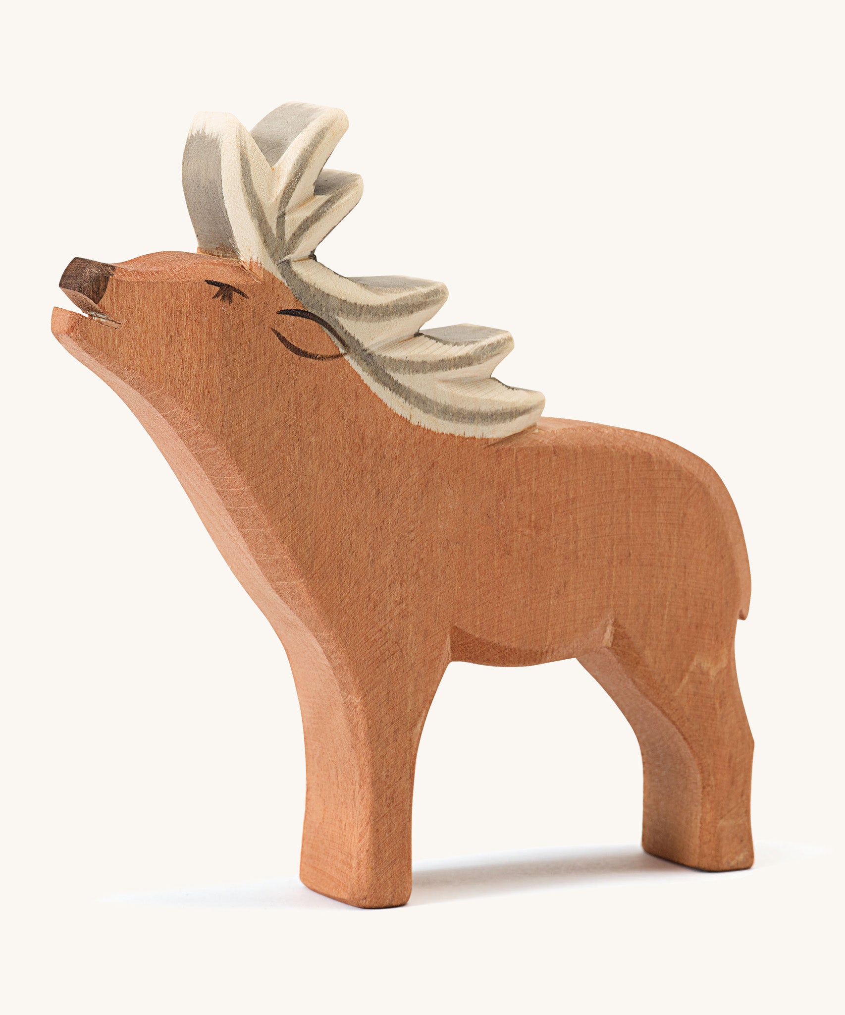 A wooden Ostheimer red deer stag figure on a cream background.