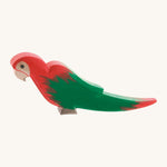 Ostheimer wooden parrot in red, with green wings on a cream background.