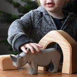 The large Ostheimer rhino wooden toy figure placed on a wooden surface. These wooden figures are part of a wide range of expertly hand crafted wooden toys here at Babipur.