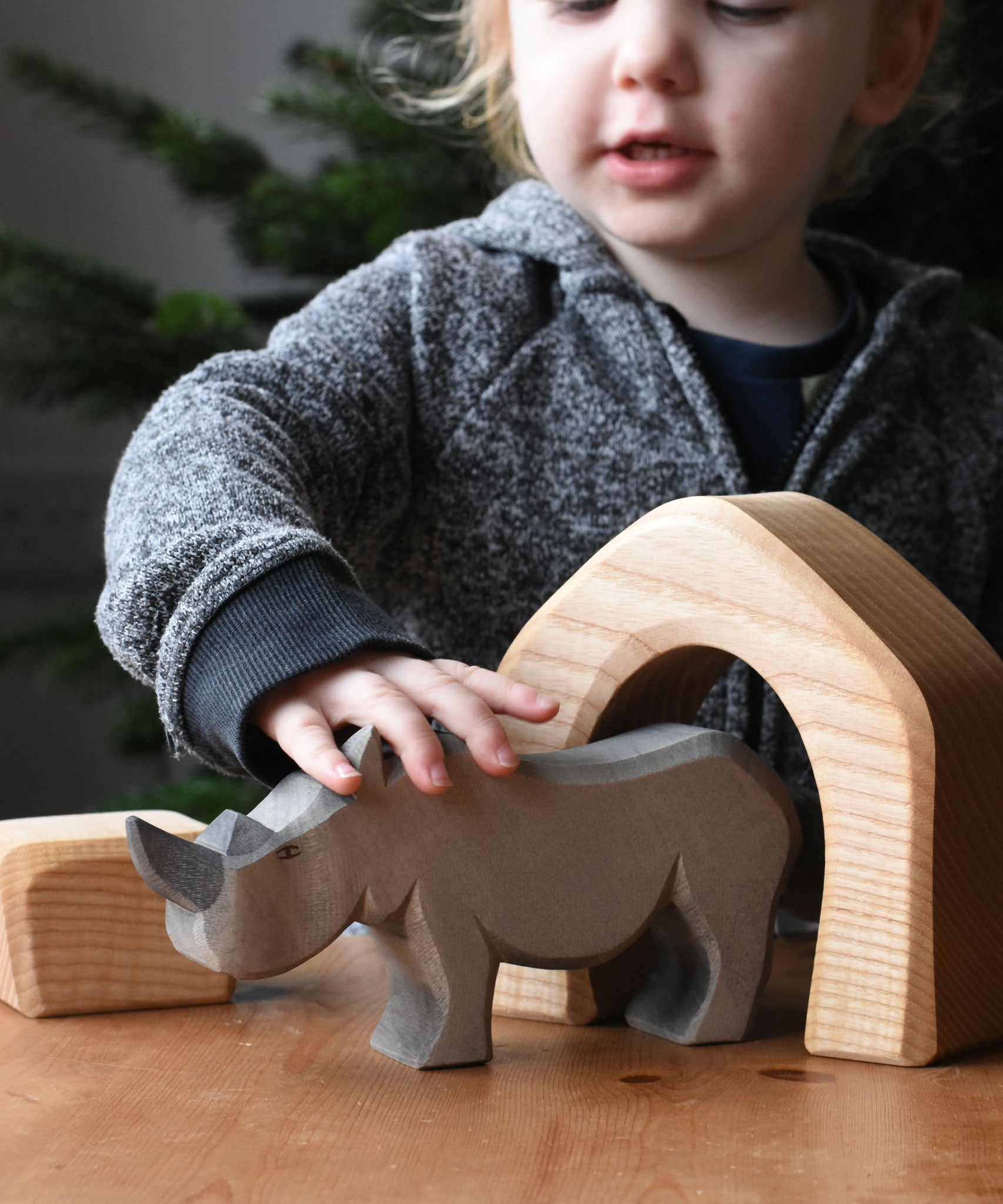The large Ostheimer rhino wooden toy figure placed on a wooden surface. These wooden figures are part of a wide range of expertly hand crafted wooden toys here at Babipur.