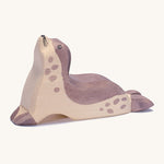 A wooden Ostheimer sea lion figure with its head held high on a cream background.