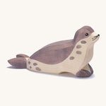 A wooden Ostheimer sea lion figure with its head low on a cream background.