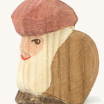 A wooden sitting dwarf wearing a brown top and a purple hat on a cream background.