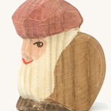A wooden sitting dwarf wearing a brown top and a purple hat on a cream background.
