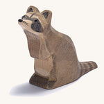 A wooden Ostheimer sitting raccoon figure on a cream background.