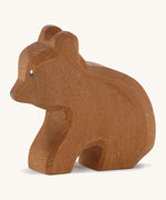 A Ostheimer wooden small brown sitting bear on a cream background.